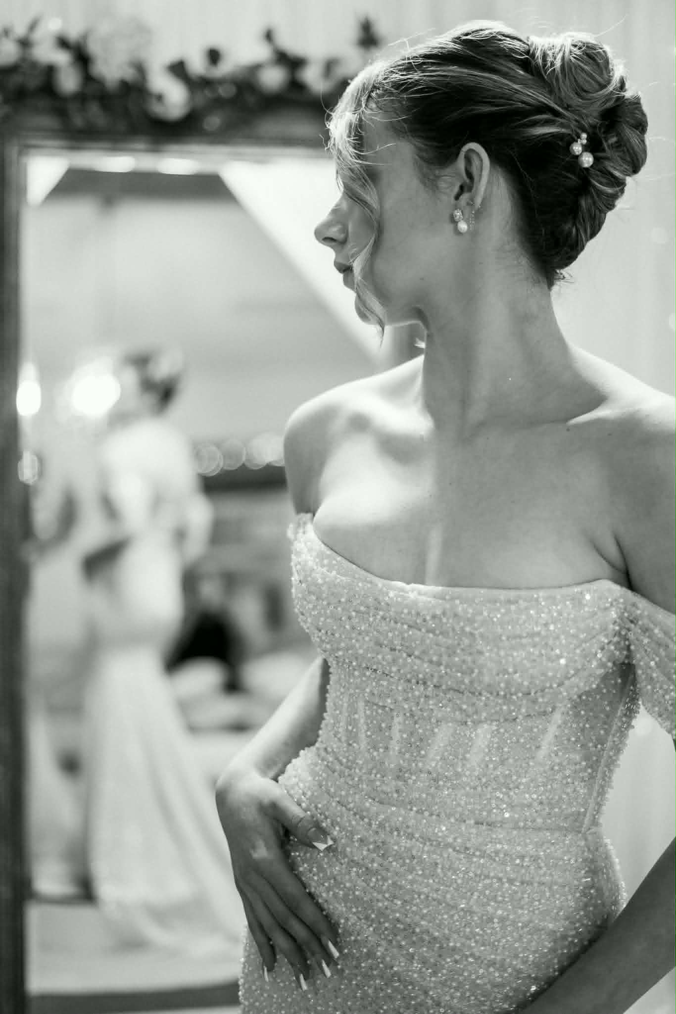 Black and white portrait of a structured bridal updo with pearl pins, mirror reflection